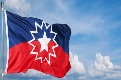 The Juneteenth flag waving on a flag pole.