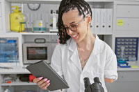 A smiling Hispanic amputee woman, confidently mastering her touchpad in a hi-tech lab.