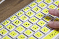 Hands typing on a braille keyboard.