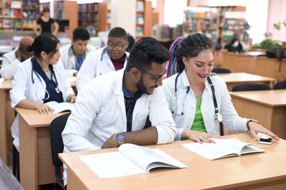 In a diverse classroom setting two students at a table consult their textbooks.