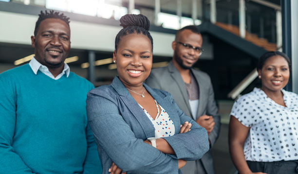 A confident Black businesswoman with a small group of Black people behind her.