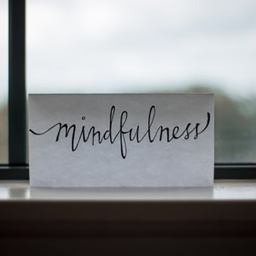 Paper near window with print that reads mindfulness