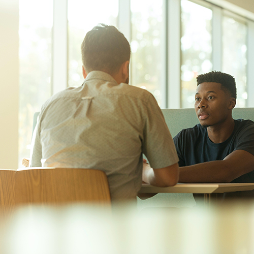 Two men sitting at a table face to face