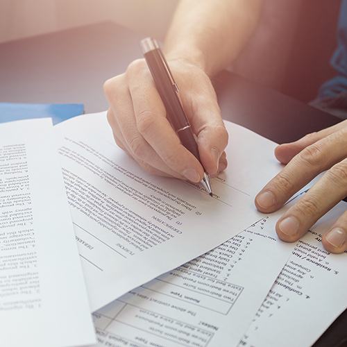 Hands signing several documents