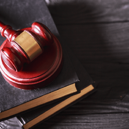 A gavel resting on a sound block and a stack of law books