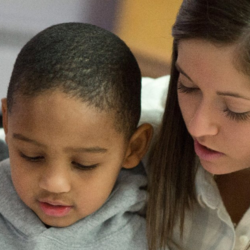 A white healthcare working sitting with a young black child