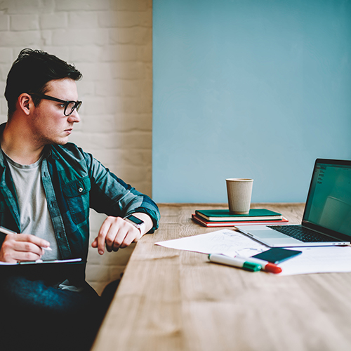 A male sitting at table with laptop and notebook