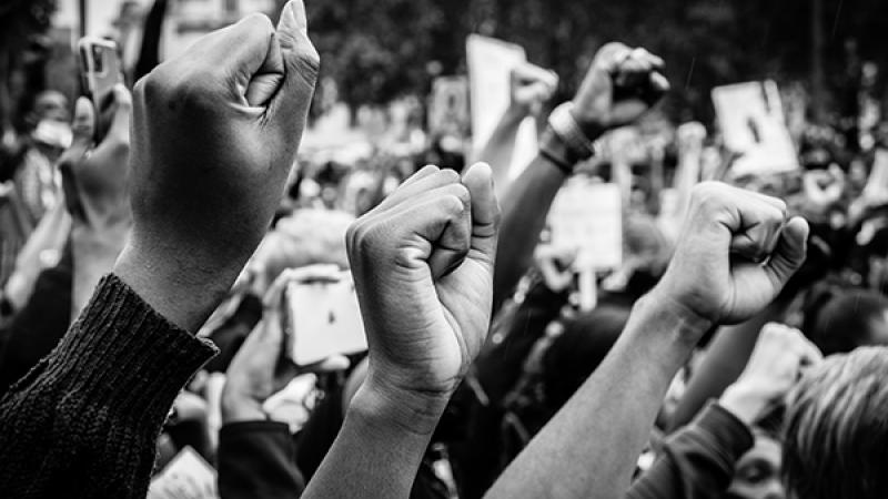 Crowd holding fists in unison at rally.