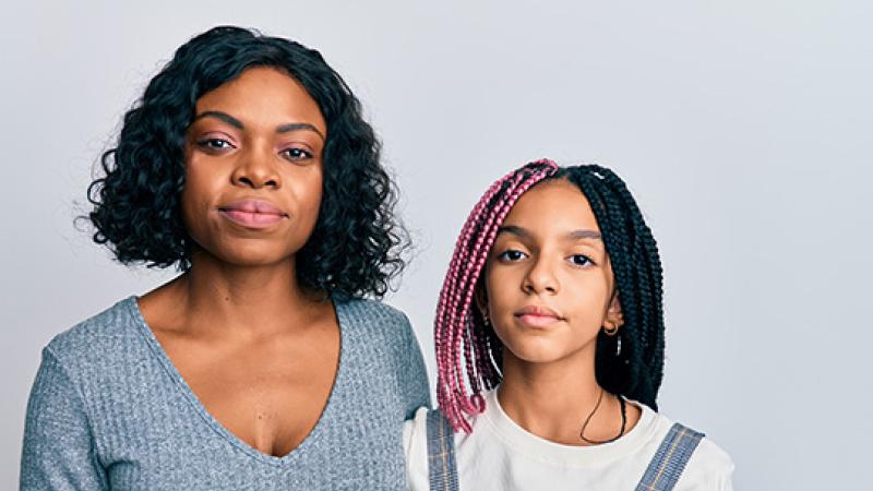 A mother and daughter both look at the camera.