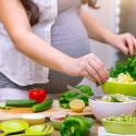 A pregnant person preparing food in the kitchen.